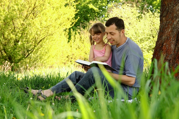 Giovane padre con una figlia piccola che legge la Bibbia