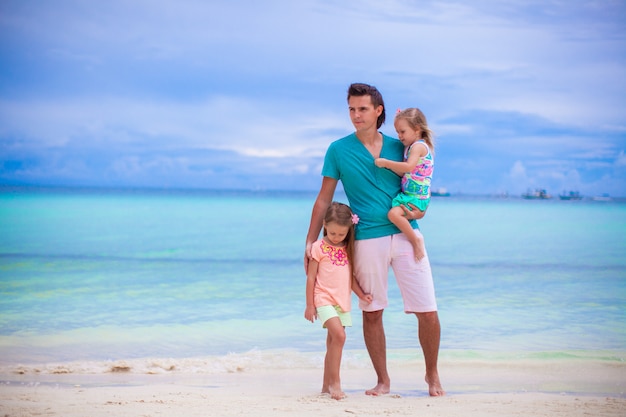 Giovane padre e due bambini che camminano vicino al mare