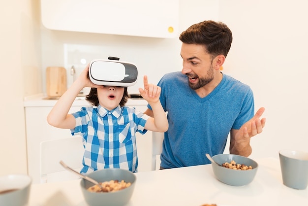 Giovane padre e figlio che usando i vetri di VR a casa.