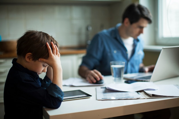 Giovane padre padre e ragazzino che per mezzo della compressa digitale