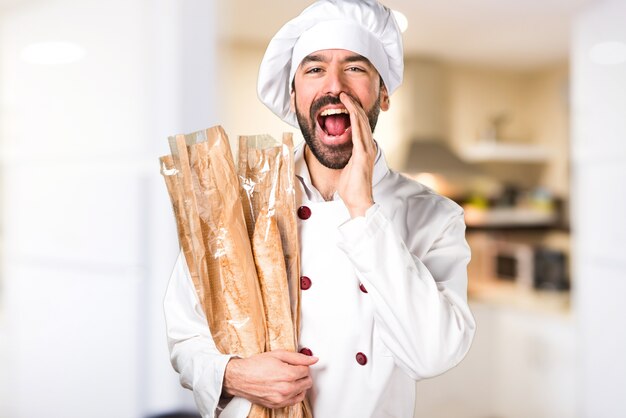 Giovane panettiere che tiene un po &#39;di pane e grida in cucina