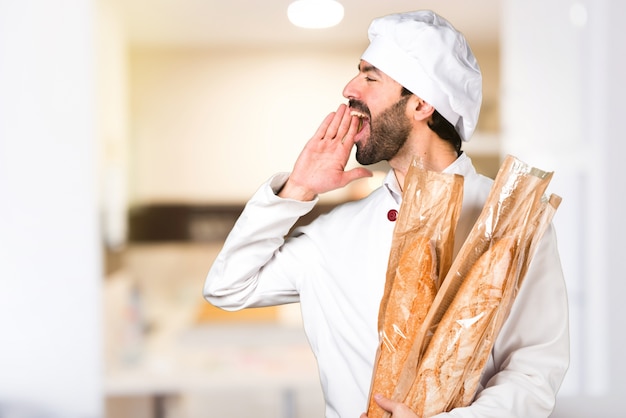 Giovane panettiere che tiene un po &#39;di pane e grida in cucina