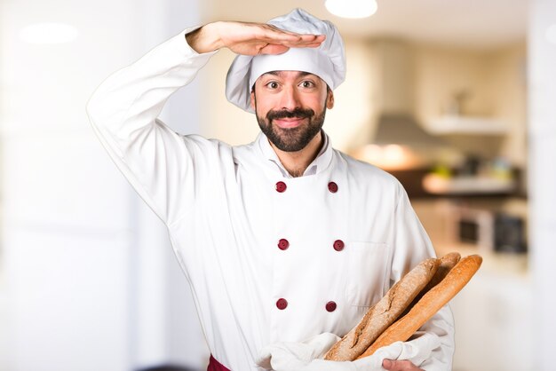 Giovane panettiere che tiene un po &#39;di pane e mostra qualcosa in cucina