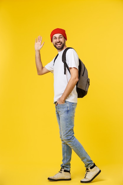 Giovane pantaloni a vita bassa uomo indossa il cappello, bretelle, isolato su giallo.