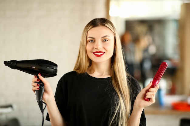 Giovane parrucchiere che tiene phon e spazzola per capelli