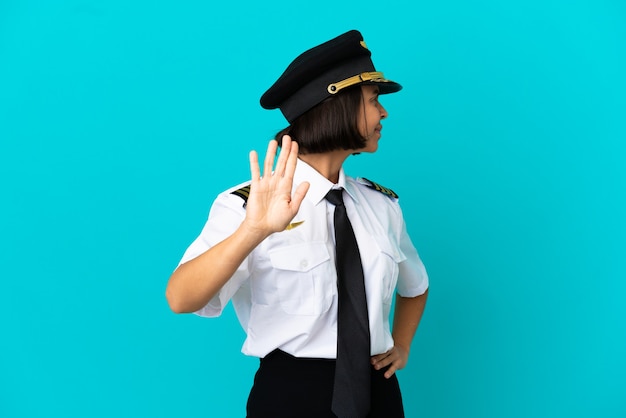 Giovane pilota di aeroplano su sfondo blu isolato facendo gesto di arresto e deluso