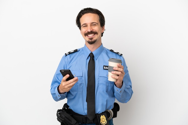 Giovane poliziotto su sfondo bianco isolato che tiene caffè da portare via e un cellulare