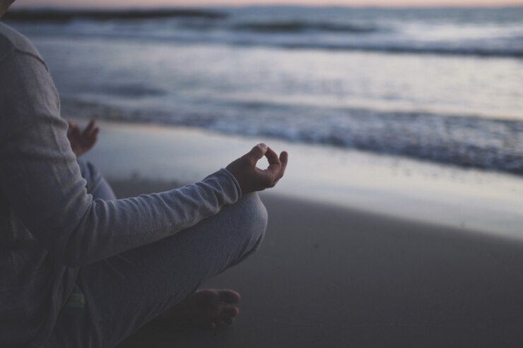 Foto giovane pratica yoga sulla spiaggia al tramonto.