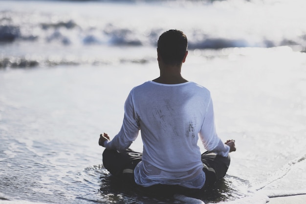 Giovane pratica yoga sulla spiaggia al tramonto.