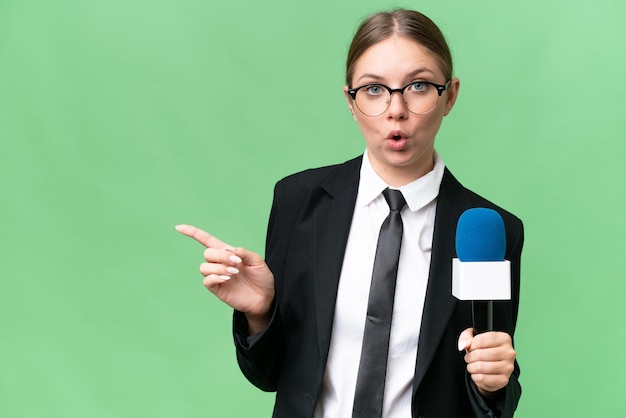 Giovane presentatore televisivo donna caucasica su sfondo isolato sorpreso e indicando il lato