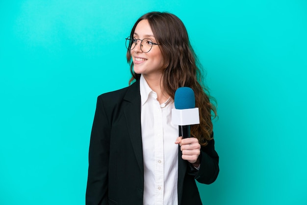 Giovane presentatore televisivo donna isolata su sfondo blu guardando lato