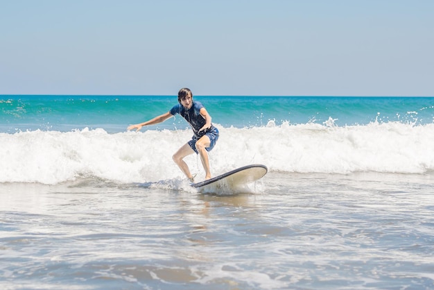 Giovane, principiante Il surfista impara a fare surf su una schiuma marina sull'isola di Bali