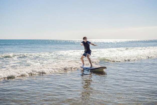 Giovane, principiante Il surfista impara a fare surf su una schiuma marina sull'isola di Bali