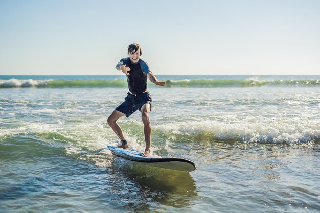 Giovane, principiante Il surfista impara a fare surf su una schiuma marina sull'isola di Bali