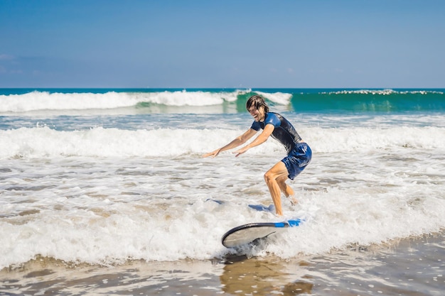 Giovane, principiante Il surfista impara a fare surf su una schiuma marina sull'isola di Bali