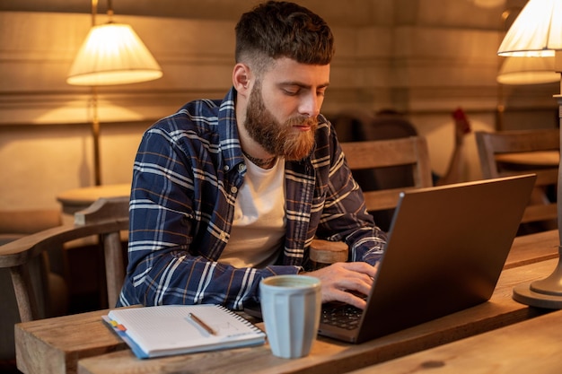 Giovane professionista che naviga in Internet sul suo laptop in un bar