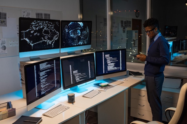 Giovane programmatore africano che manda messaggi sullo smartphone dal posto di lavoro