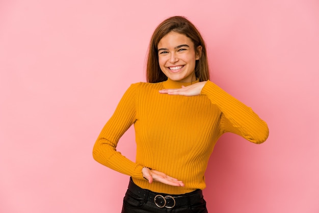 Giovane ragazza adolescente caucasica magra che tiene qualcosa con entrambe le mani, presentazione del prodotto.