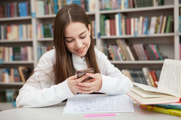 Giovane ragazza adolescente che studia in biblioteca