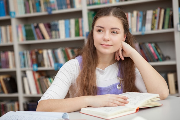 Giovane ragazza adolescente che studia in biblioteca