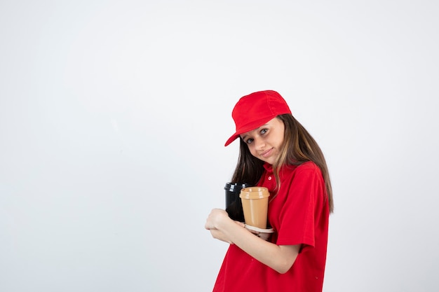 giovane ragazza adolescente in uniforme rossa che tiene due tazze di caffè in una scatola