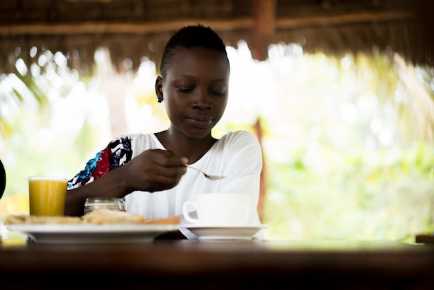 Giovane ragazza africana nel resort facendo colazione