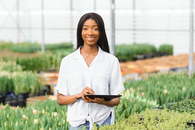 Giovane ragazza afroamericana, lavoratore con fiori in serra.