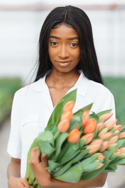 Giovane ragazza afroamericana, lavoratore con fiori in serra.