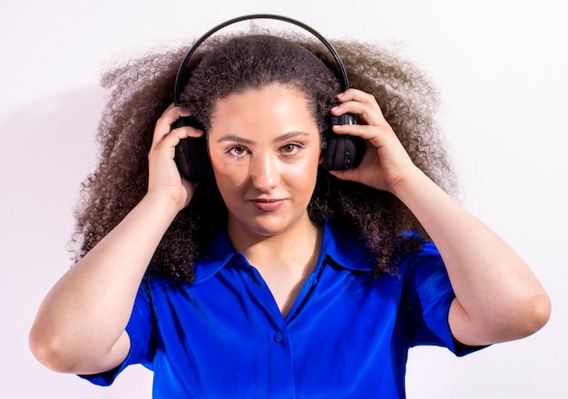 Giovane ragazza afrohaired che ascolta la musica con le cuffie su fondo bianco isolato