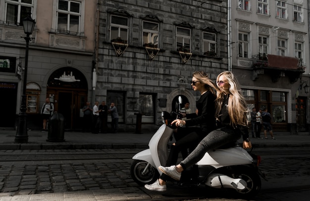 Giovane ragazza allegra con scooter in città europea