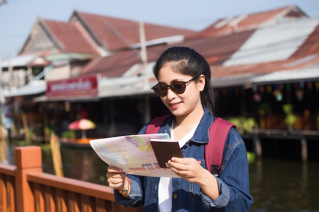 Giovane ragazza asiatica che cammina al mercato di galleggiamento del saduak di Dumonoe, Tailandia