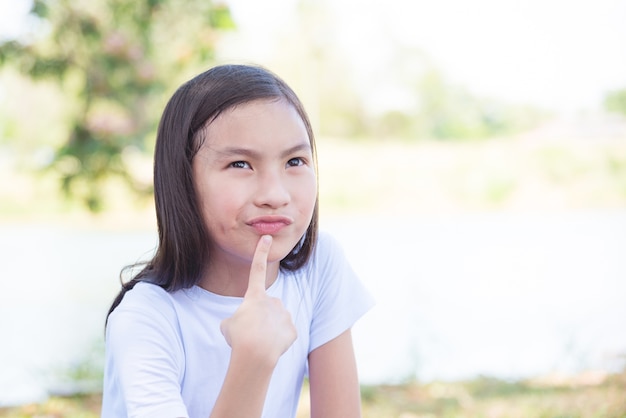 Giovane ragazza asiatica che pensa nel parco