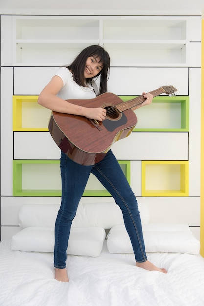 Giovane ragazza asiatica che suona la chitarra nella sua camera da letto