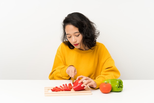 Giovane ragazza asiatica con le verdure in una tabella