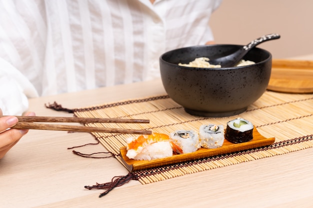 Giovane ragazza asiatica in un tavolo con una ciotola di noodles e sushi