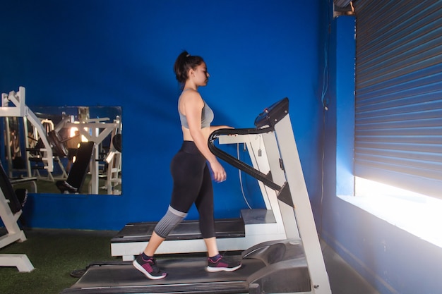 Giovane ragazza atletica che utilizza il tapis roulant in palestra.