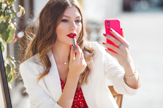 Giovane ragazza attraente che fa selfie sul telefono cellulare. Ritratto alto vicino della bella donna all'aperto. Signora graziosa che tiene cellulare.