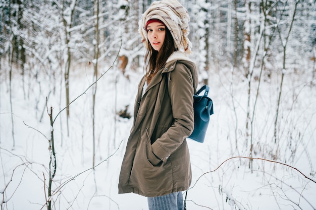 Giovane ragazza attraente con un turbante dalla sciarpa in posa nella foresta di neve