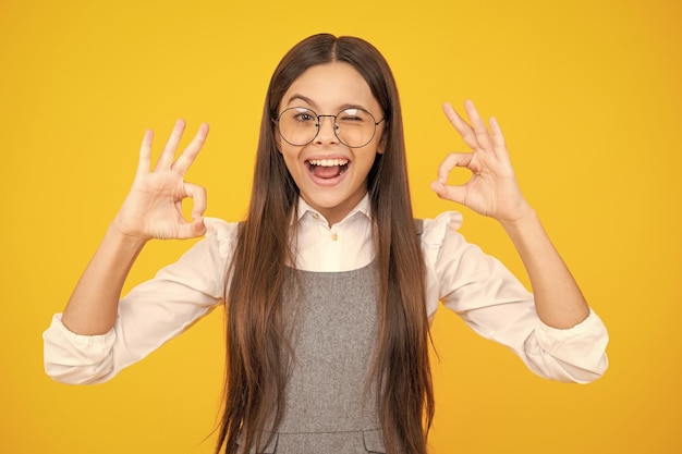 Giovane ragazza bambino mostra dita ok simbolo linguaggio dei segni isolato su sfondo giallo Adolescente divertente