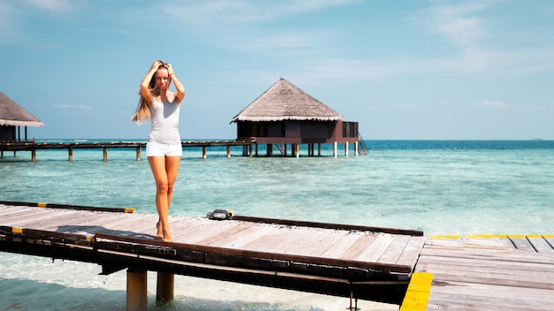 Giovane ragazza bionda attraente con corpo sportivo perfetto in bikini sulla spiaggia estiva tropicale