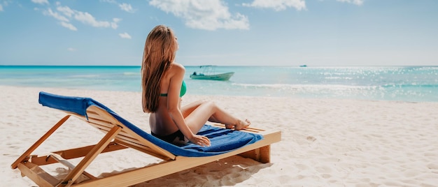 Giovane ragazza bionda attraente con un corpo sportivo perfetto in bikini sulla spiaggia tropicale estiva