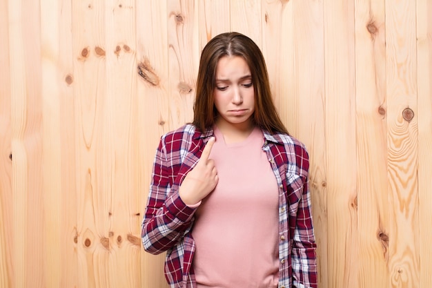 Giovane ragazza bionda contro la parete di legno