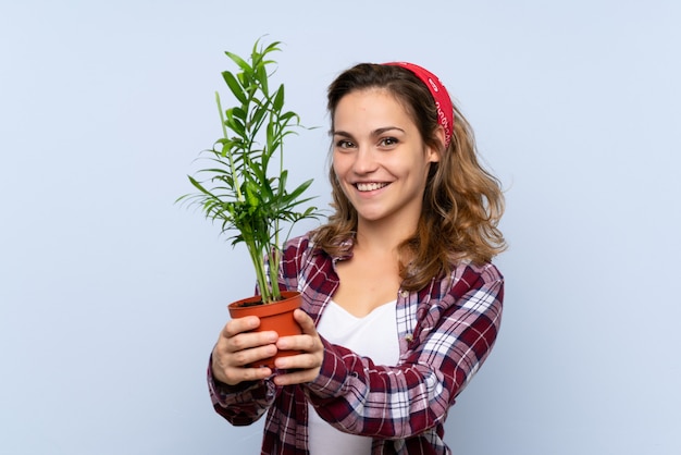 Giovane ragazza bionda del giardiniere che tiene un blu della pianta