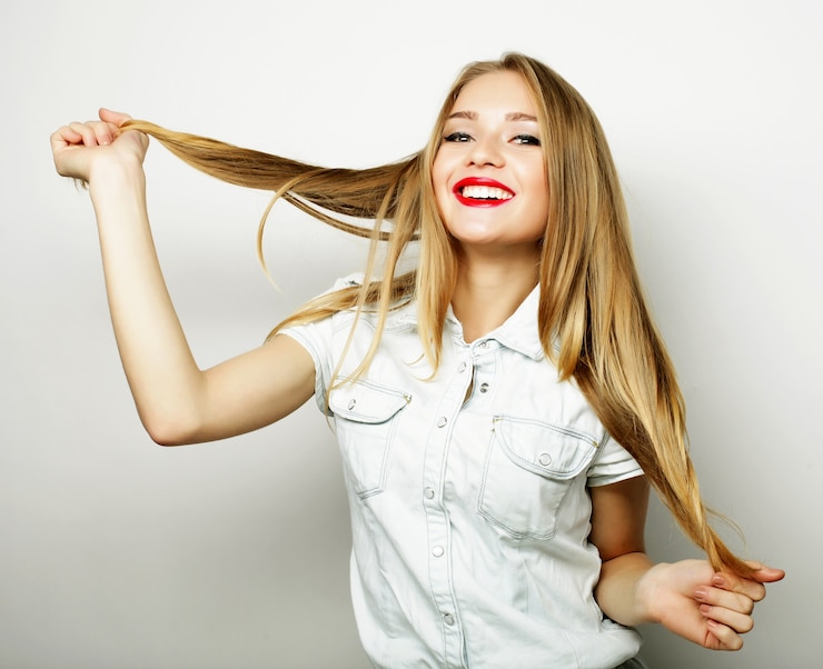 Foto giovane ragazza bionda sorridente carina su sfondo bianco