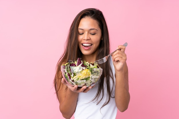 Giovane ragazza brasiliana con insalata sana sopra il rosa