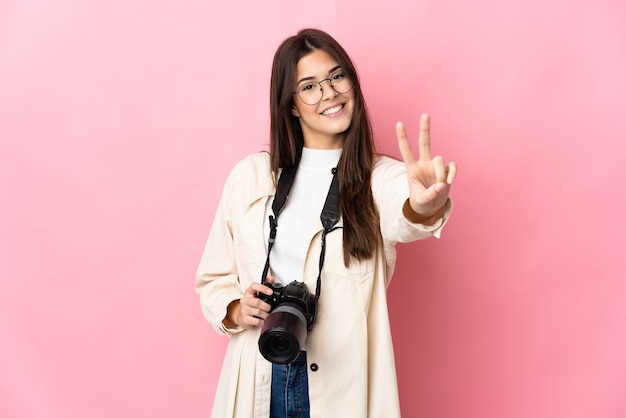 Giovane ragazza brasiliana del fotografo isolata sul colore rosa che sorride e che mostra il segno di vittoria