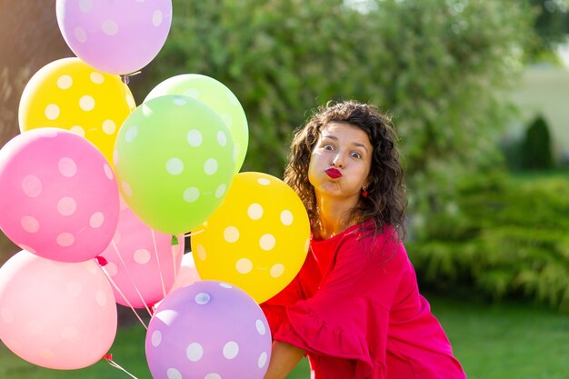 Giovane ragazza bruna gioiosa brillante con palloncini colorati. Stile di vita felice.