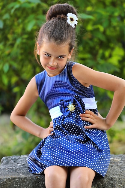 Giovane ragazza bruna in un vestito blu nel parco in estate. Foto di alta qualità