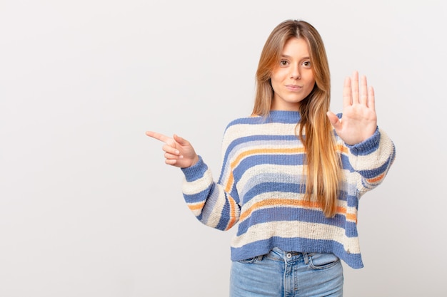 Giovane ragazza carina che sembra seria mostrando il palmo aperto che fa il gesto di arresto