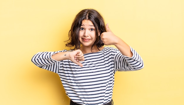 Giovane ragazza carina che si sente confusa, incapace e insicura, soppesando il bene e il male in diverse opzioni o scelte